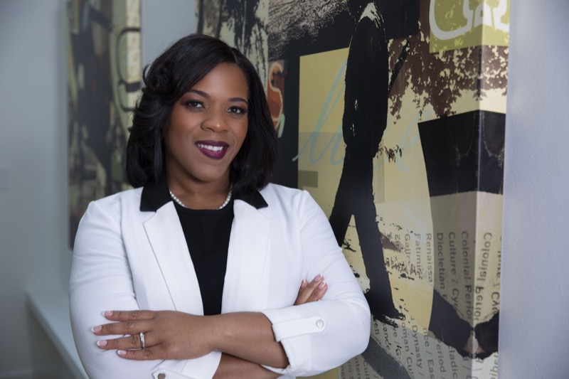 Kia, workers' compensation attorney, standing with arms crossed in a white blazer